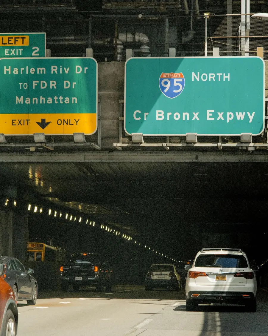 Overhead signs for I-95 North, the Cross Bronx Expressway, and the Harlem River Drive exit above traffic heading into the underpass