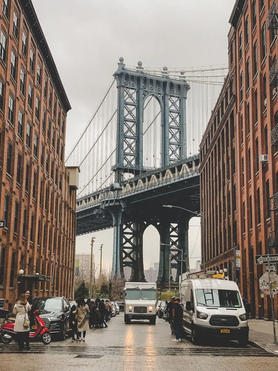 The Manhattan Bridge framed between red-brick warehouses on Washington Street in DUMBO, on a grey day