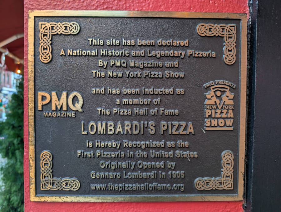 The Pizza Hall of Fame plaque outside Lombardi's, recognizing it as the first pizzeria in the United States, opened by Gennaro Lombardi in 1905