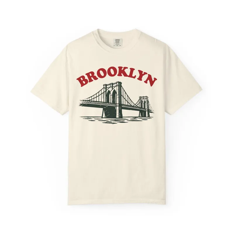 A cream t-shirt reading Brooklyn over an illustration of the Brooklyn Bridge